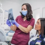 Oral surgeon and patient looking at x-rays of wisdom teeth to determine if wisdom teeth extraction is necessary.