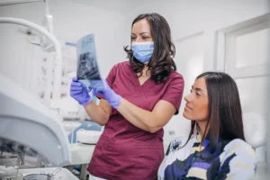 Oral surgeon and patient looking at x-rays of wisdom teeth to determine if wisdom teeth extraction is necessary.