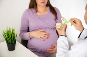 Photo of pregnant woman discussing wisdom tooth extraction during pregnancy.