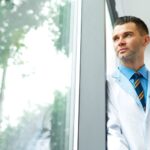 A doctor looking out a window contemplating their success.