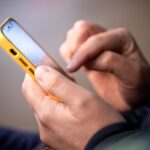 Smartphone in male hands. Close up of hands with a phone. Outdoor photo