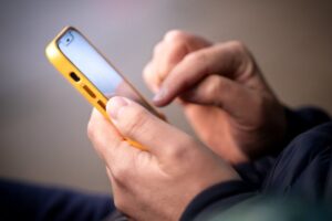 Smartphone in male hands. Close up of hands with a phone. Outdoor photo