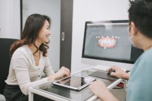 A doctor review a 3d image of her patients mouth with them