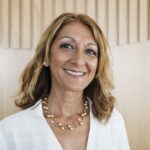 Smiling woman with gold necklace and white shirt