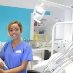 A young, smiling staff member in a dental exam room ready to help their boss